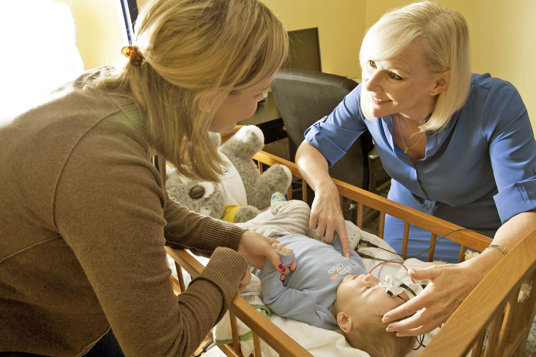 A woman holding a baby while a provider examines the baby's ear